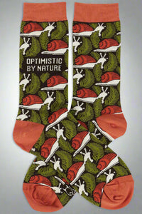 A pair of crew socks with fern leaves and snails on them. It reads ‘optimistic by nature’ on the ankle.
