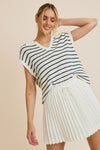 Model is wearing a drop shoulder collared v neck sleeveless sweater top with blue and white stripes.