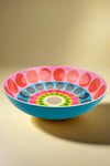 A large salad bowl that is bright blue on the outside and has a brightly colored dot pattern on the inside.