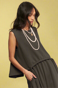 Model is wearing a soft knit high-low muscle tank with a front tie detail. 