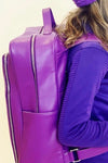 A purple , vegan leather backpack with zipper closures.