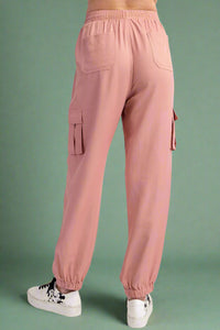 Pink cargo jogger pants worn by a person on a white background