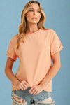 Woman wearing a peach-colored t-shirt and denim shorts on a beige background