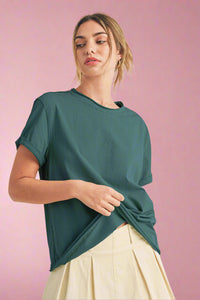 Woman wearing a teal top with a beige background