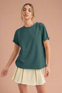 Woman wearing a teal t-shirt and beige skirt on a beige background