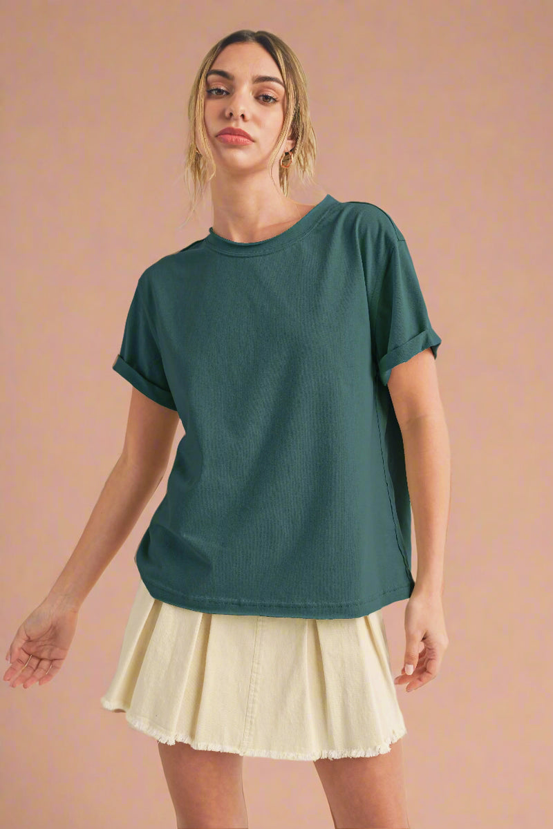 Woman wearing a teal t-shirt and beige skirt on a beige background