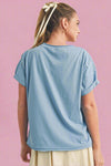 Person wearing a light blue t-shirt on a beige background