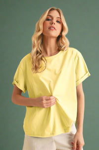 Woman wearing a yellow top and white shorts against a beige background