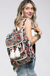 Handmade embellished flap backpack with an outside pocket, adjustable straps, tassels, and a vibrant paisley pattern.