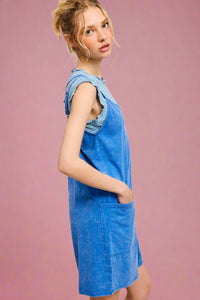 Woman wearing a blue denim dress against a light pink background