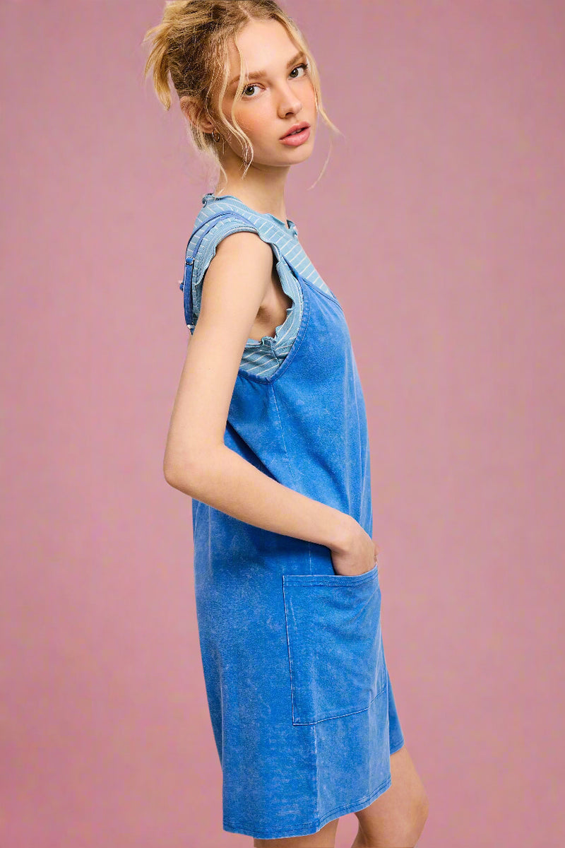 Woman wearing a blue denim dress against a light pink background
