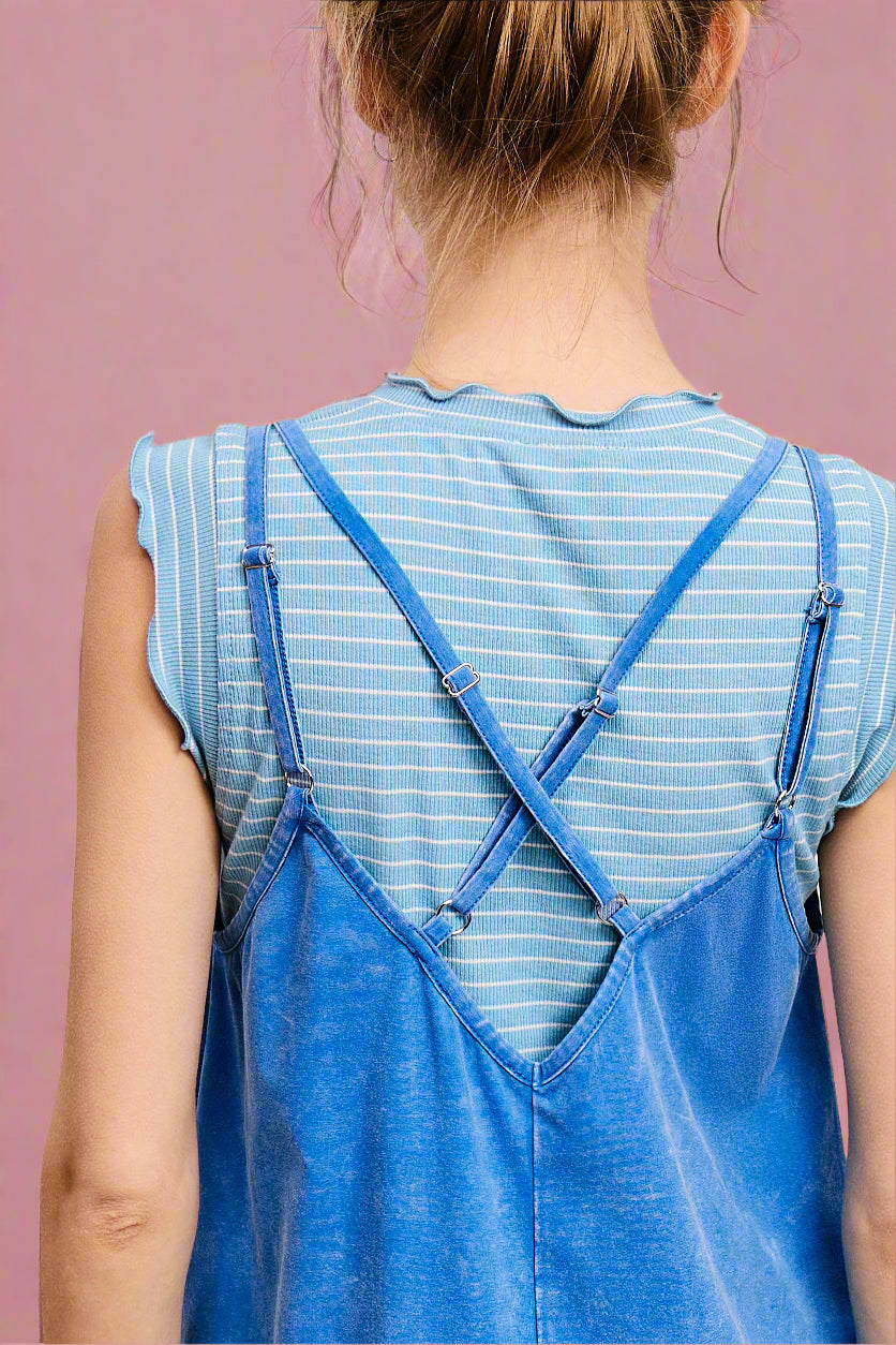 Person wearing a blue denim dress with a striped shirt underneath on a white background