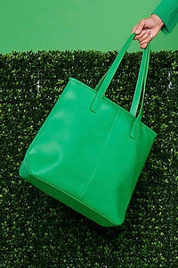 A green, vegan leather tote bag with zipper closures.