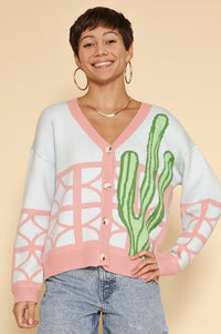 Model is wearing a colorful cardigan that features a bright cactus and geometric pattern. 