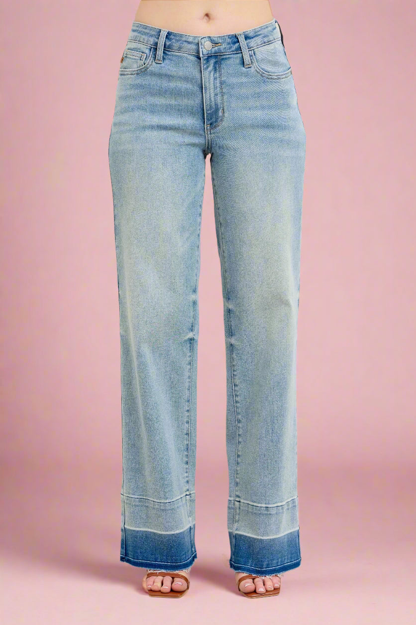 Model is wearing mid rise light wash vintage style wide leg jeans with a released hem detail.