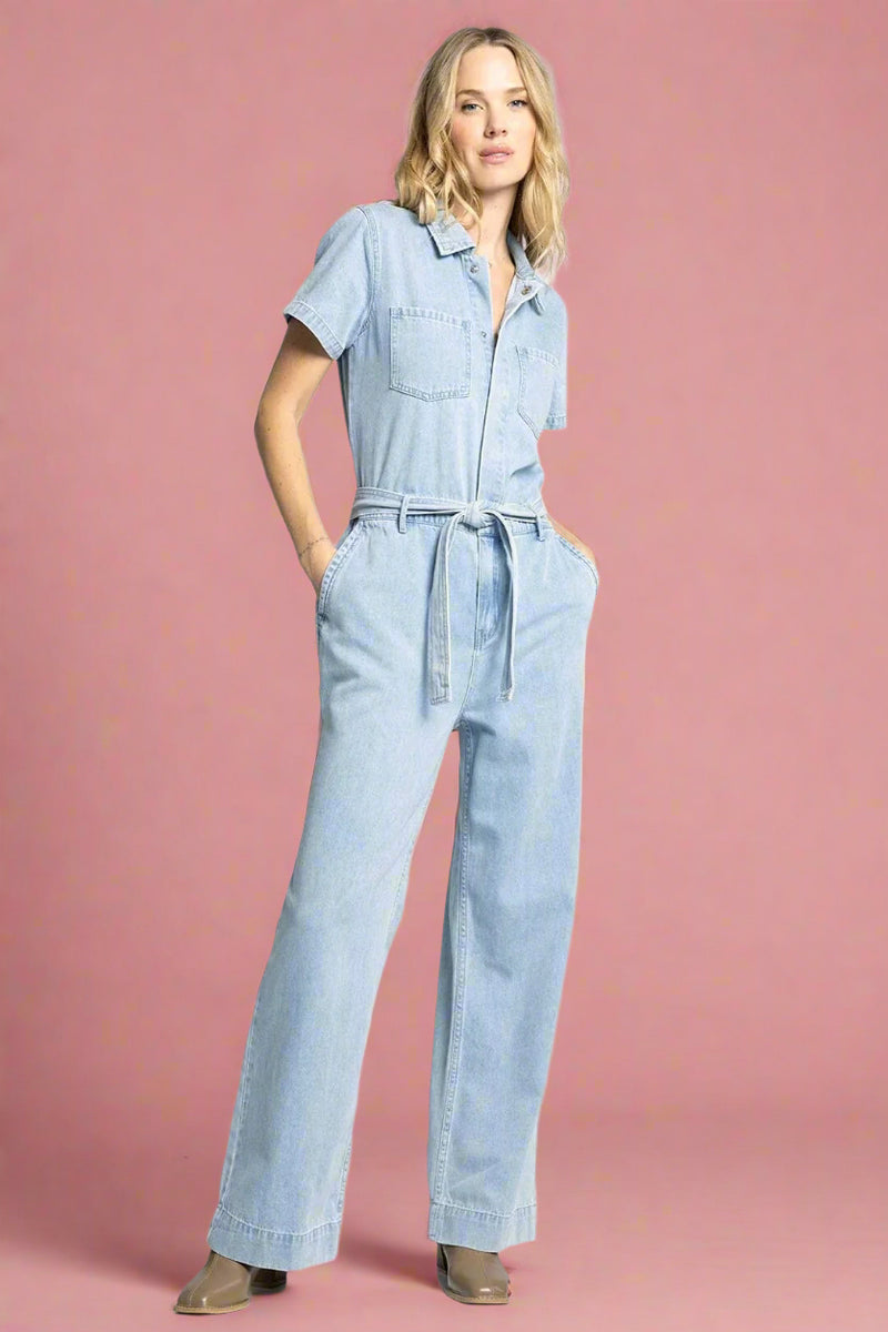 Woman wearing a light blue denim jumpsuit on a white background