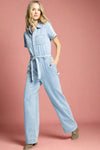 Woman wearing a light blue denim jumpsuit on a white background