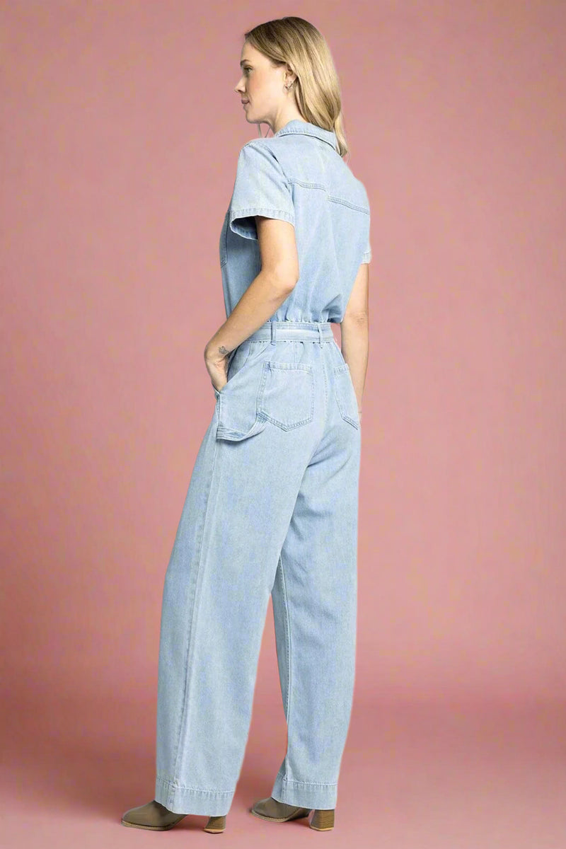 Woman wearing a light blue denim jumpsuit on a white background