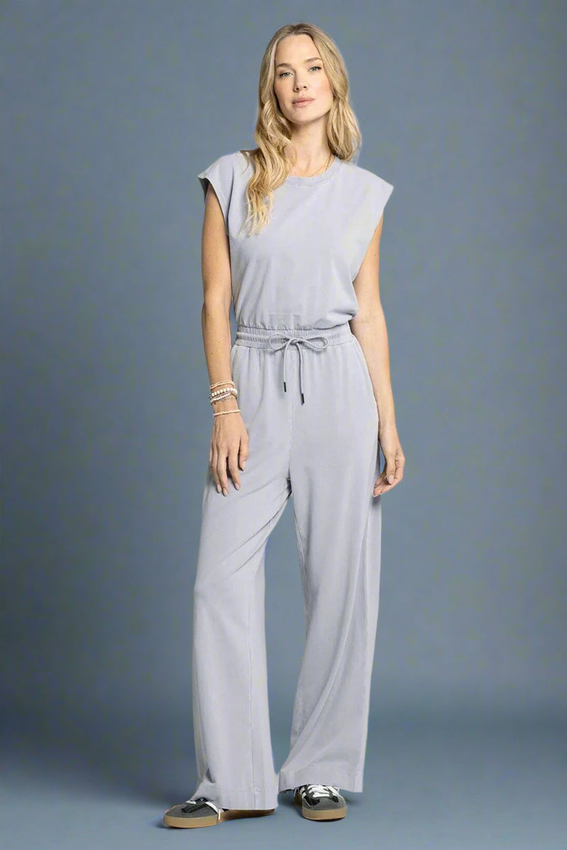 Woman wearing a light gray jumpsuit on a white background