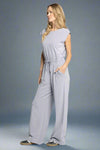 Woman wearing a light gray jumpsuit on a white background