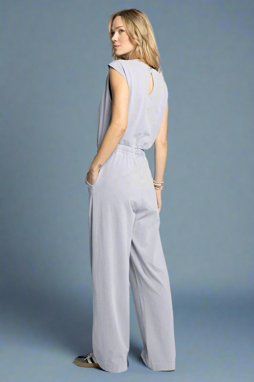 Woman wearing a light gray jumpsuit on a white background