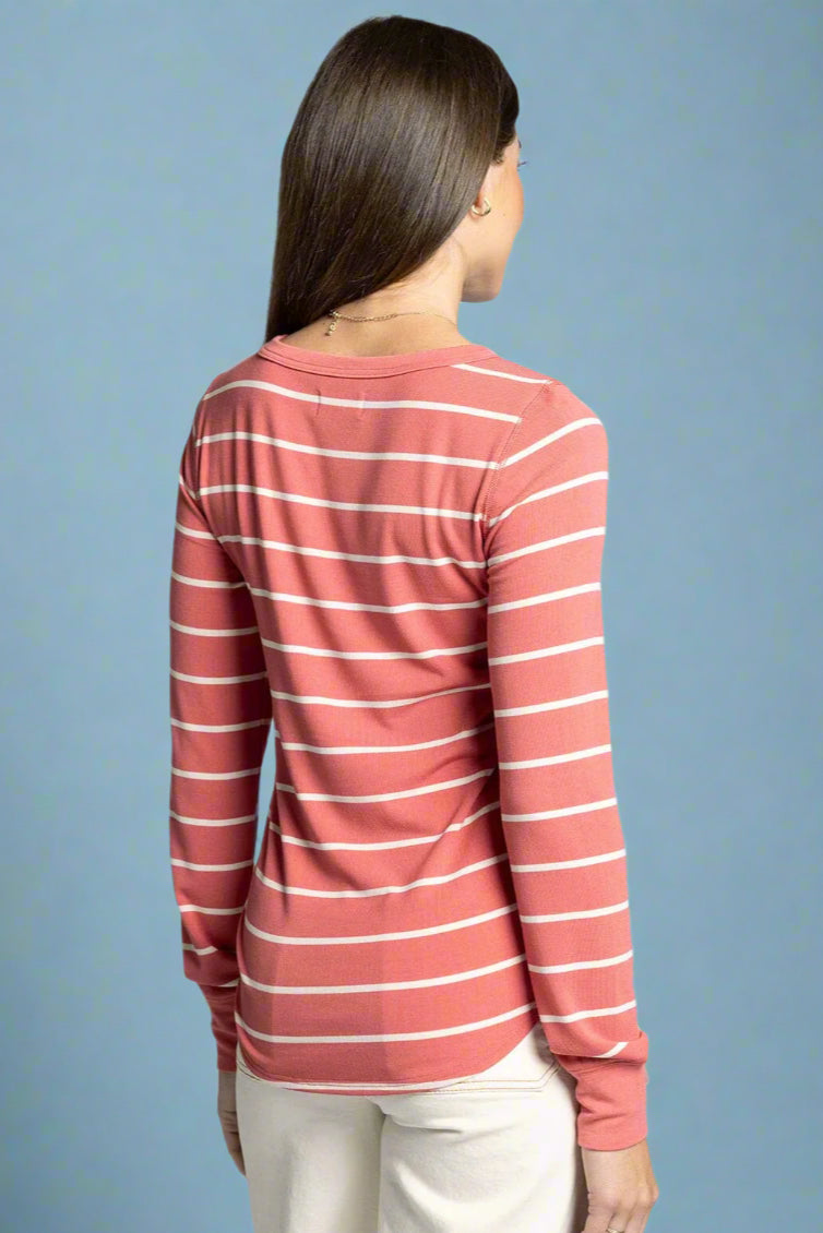 Woman wearing a pink and white striped long-sleeve shirt on a light gray background