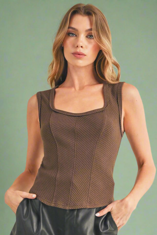 Model is wearing a cute tank in a chocolate color. Tank top has wide straps and a square neck. With diagonal ribbed panels its the perfect elevated basic. 