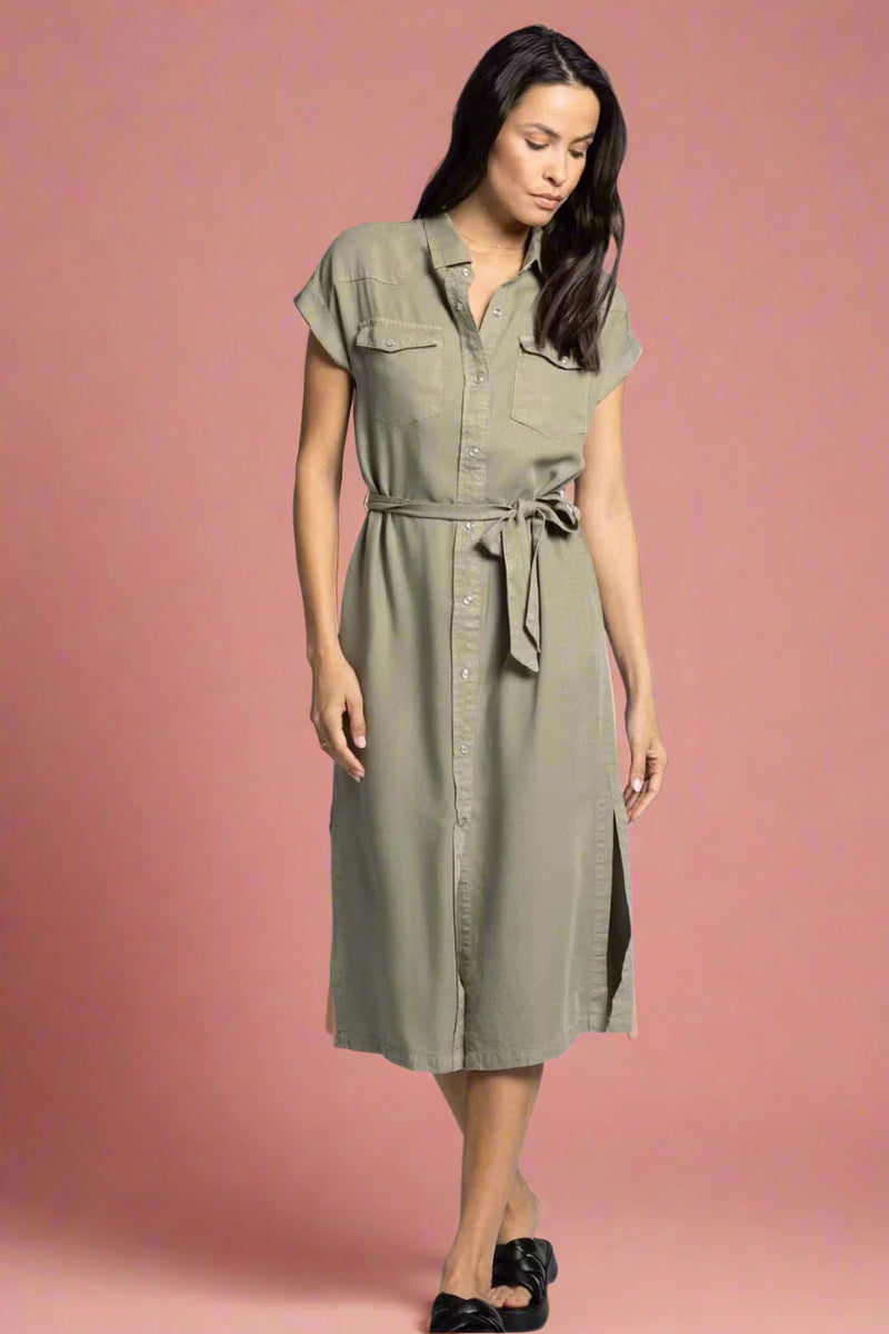 Woman wearing a green dress with a belt on a light gray background