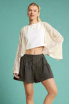 Model is wearing charcoal colored exposed fly tiered shorts with puff details.