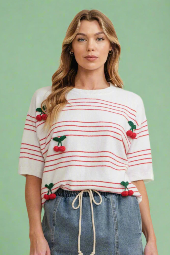 Model is wearing a red and white striped short sleeve sweater top with 3D cherry embellishments. 