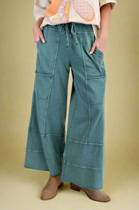 Model is wearing teal garment dyed wide leg jogger pants with unique stitch detailing.