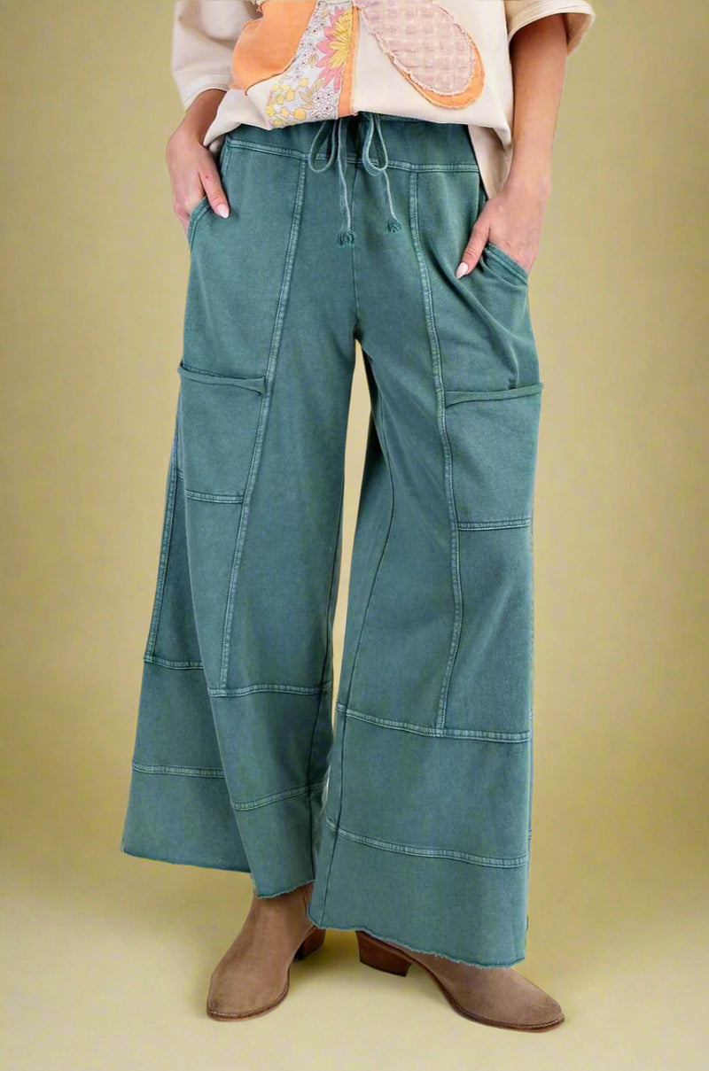 Model is wearing teal garment dyed wide leg jogger pants with unique stitch detailing.