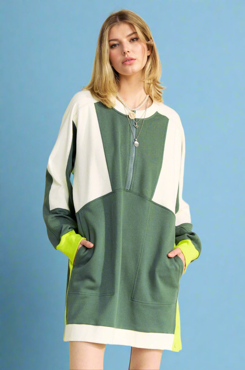 Model is wearing a long sleeve color blocked dress with pockets and a front zipper detail. 