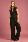 Model is wearing a long back collared jumpsuit with front buttons and an open back detail.