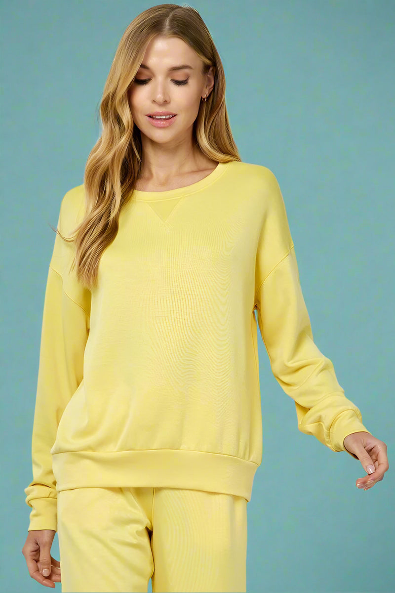 Model is wearing a buttery soft crew neck long sleeve sweatshirt in a vibrant yellow color. 