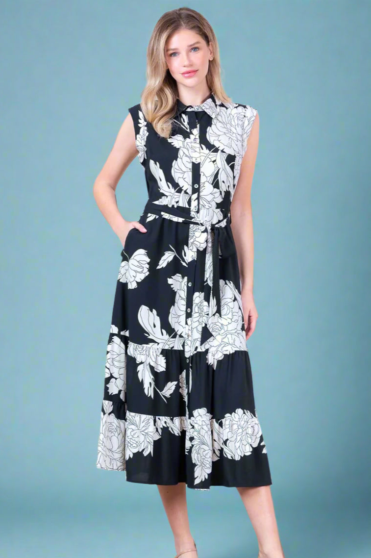 Woman wearing a black dress with white floral pattern against a white background