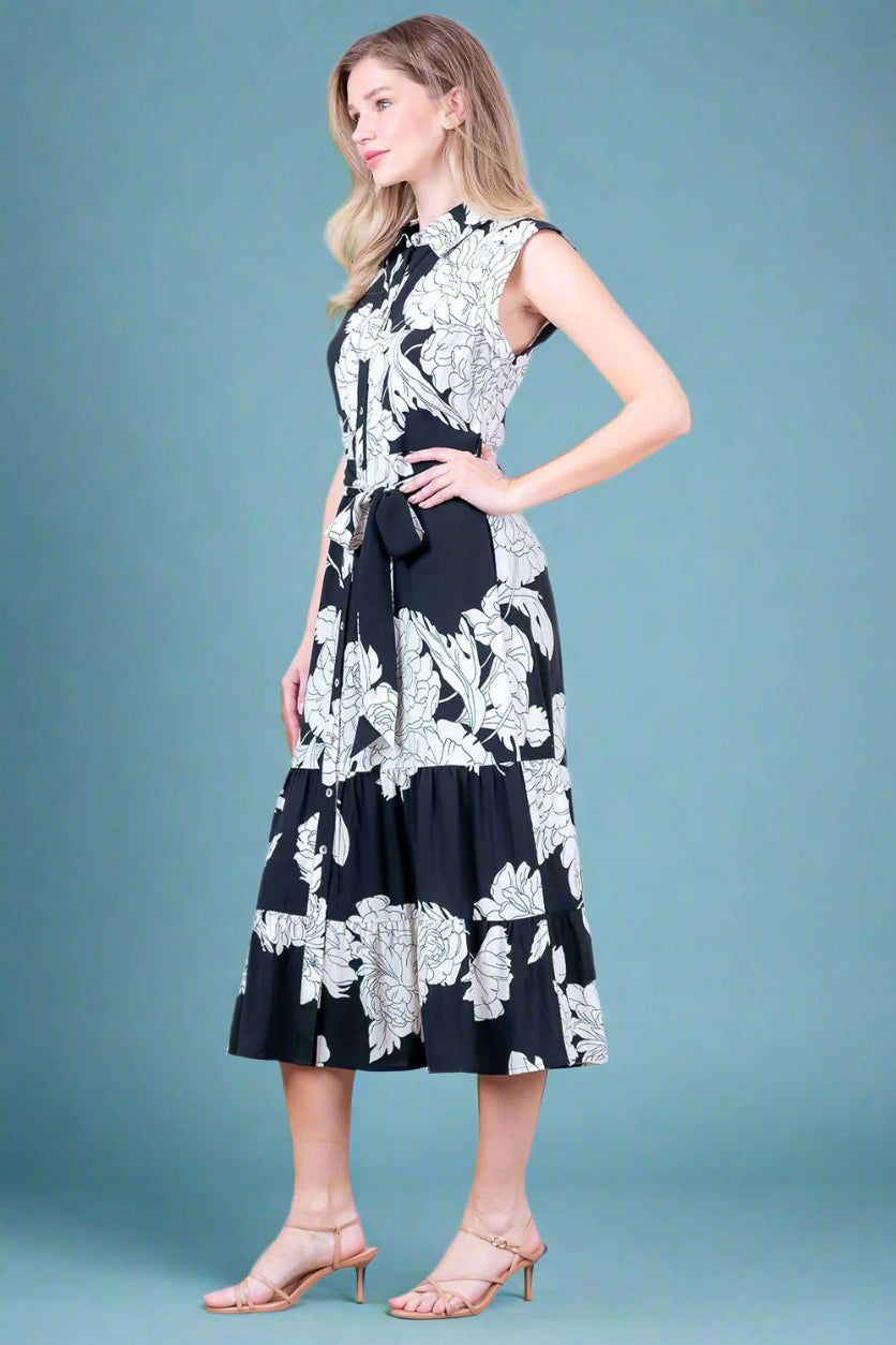 Woman wearing a black and white floral dress against a plain background