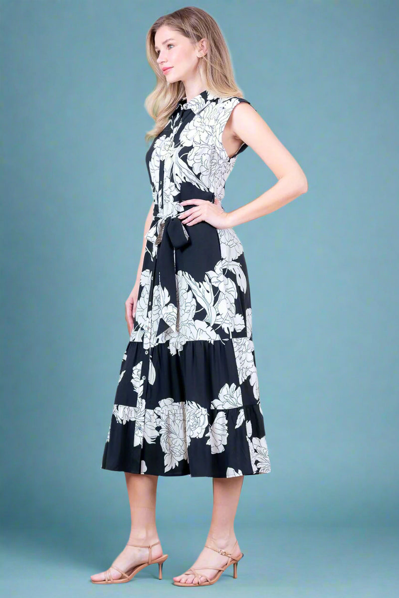 Woman wearing a black and white floral dress against a plain background