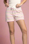 Model is wearing ultra soft sweat shorts featuring pink, brown, and orange stripes with a tie waist.