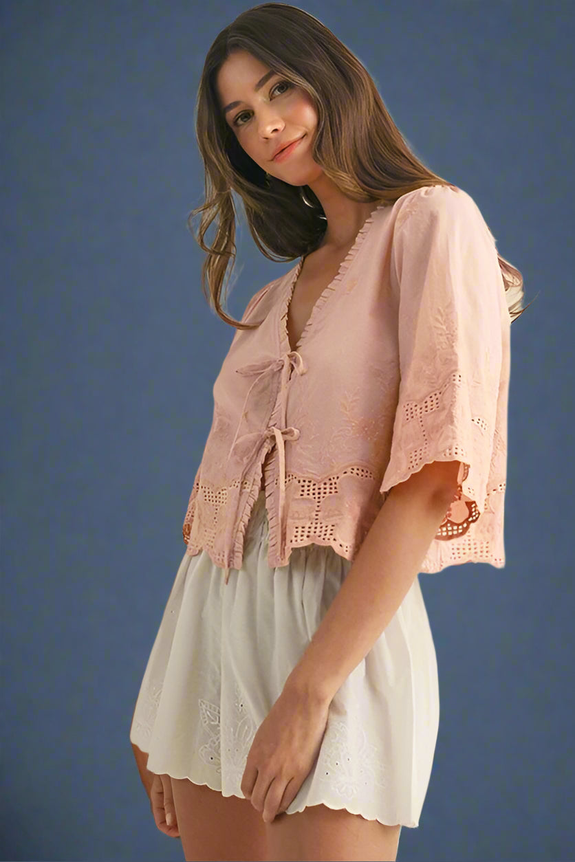 Woman wearing a pink lace top and white shorts on a beige background