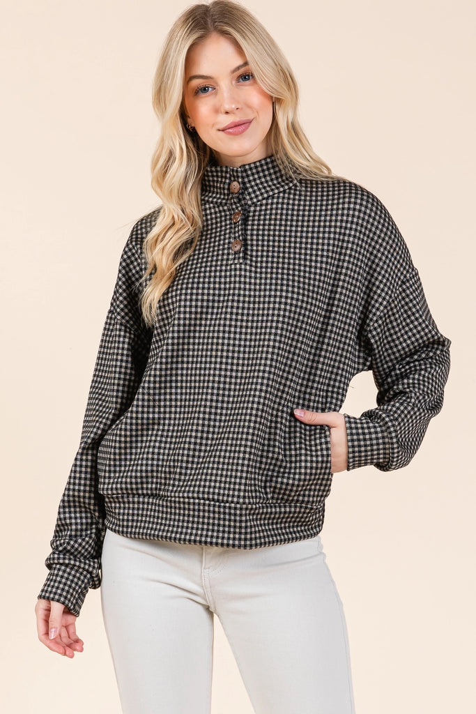 This quarter button, black checkered pullover top features side pockets.