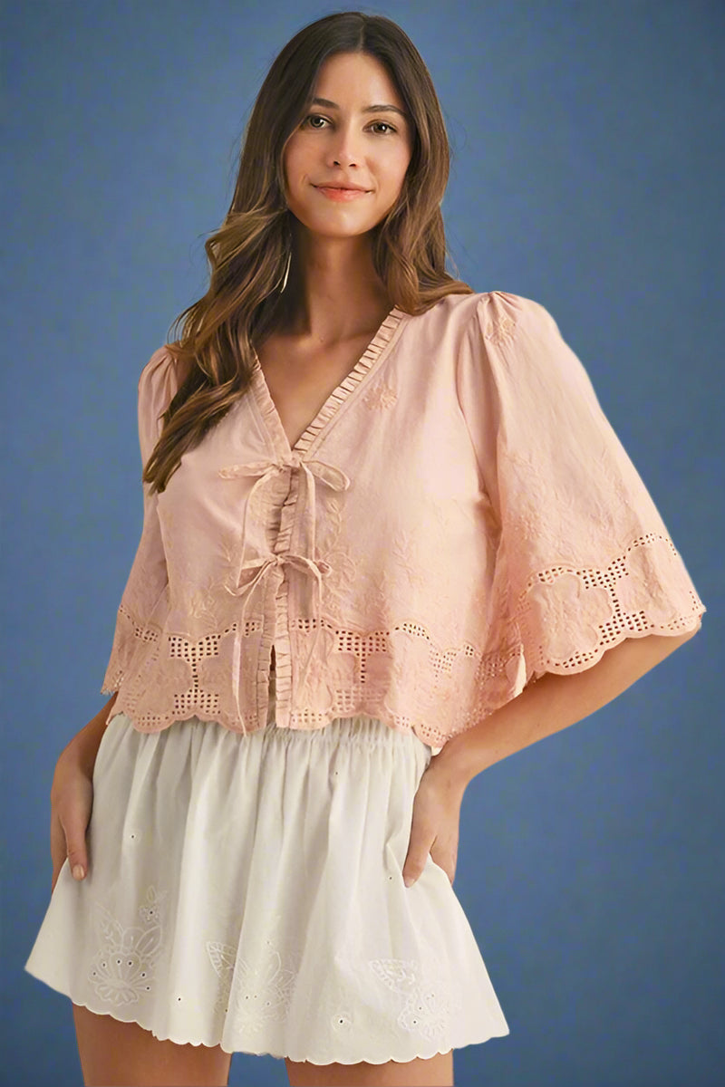 Woman wearing a pink lace top and white shorts on a beige background