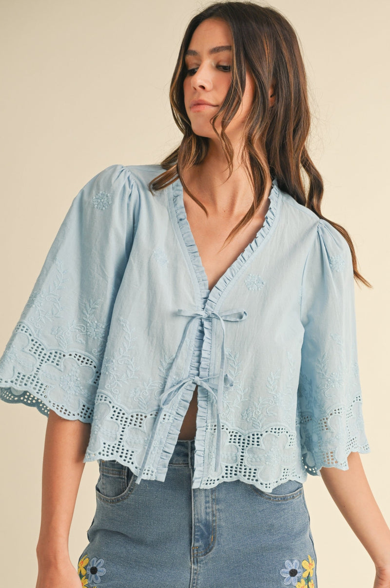 Woman wearing a light blue denim top with double bow tie