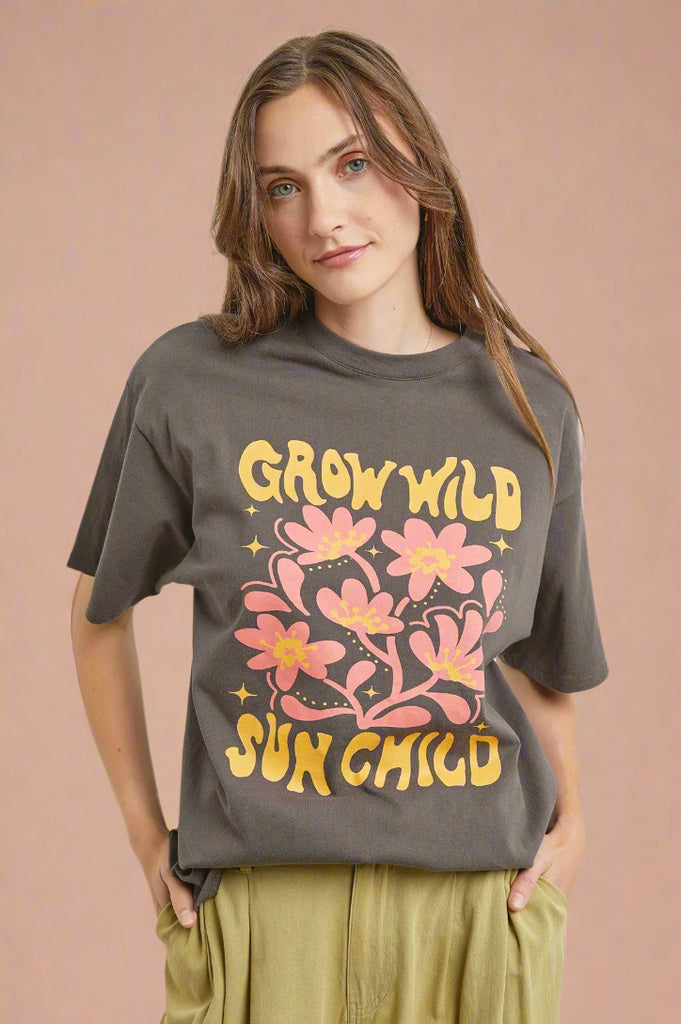 A charcoal short sleeve, graphic tee. The graphic features a floral print and says ‘Grow Wild Sun Child.’