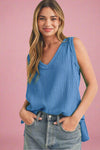Woman wearing a blue sleeveless top and jeans on a beige background