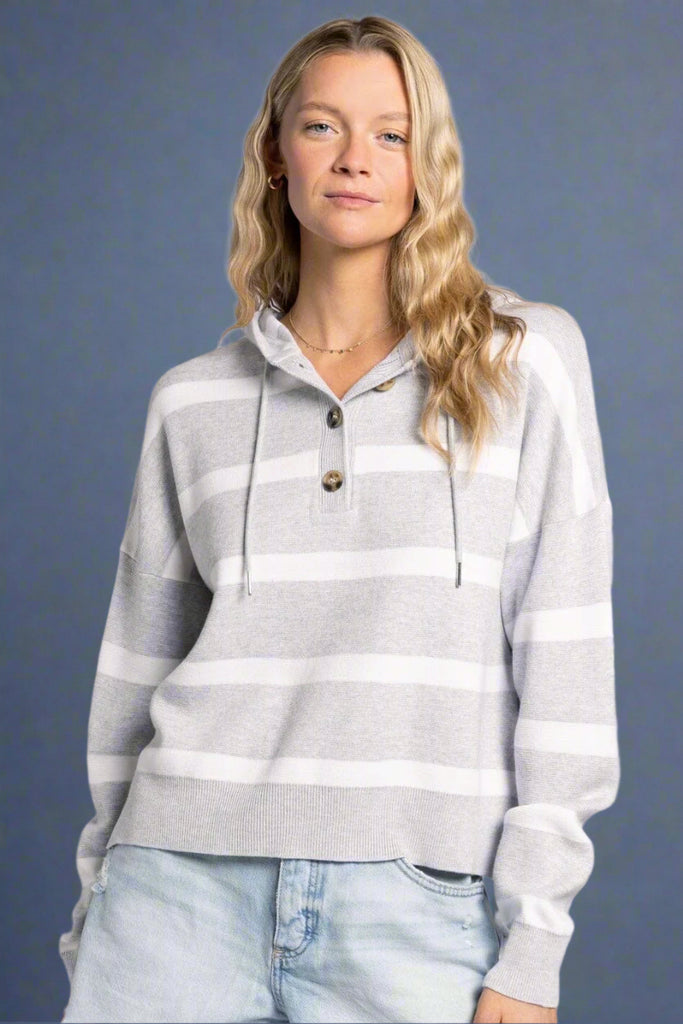 Model is wearing a quarter button up hooded top. It has grey and white horizontal stripes.