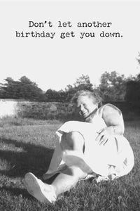 A greeting card with old black and white photo of an older woman laying in the grass with the text ‘Don’t let another birthday get you down.’