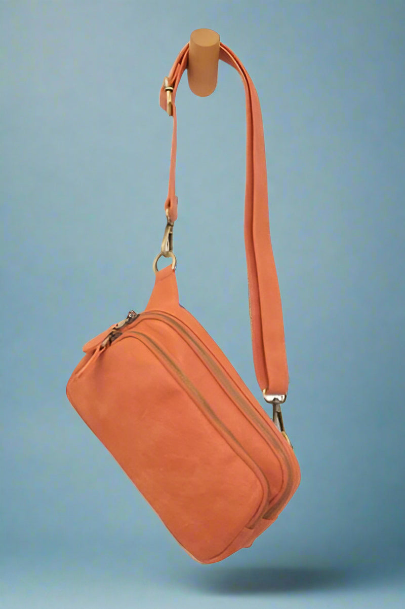 Orange, convertible sling/belt bag with a top zip closure and a front zip pocket, and crafted in super soft tumbled vegan leather.