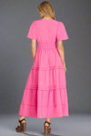 Pink dress with tiered skirt worn by a model on a grey background
