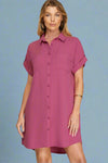 Woman wearing a magenta button-up dress against a plain background